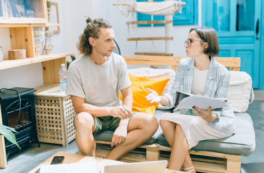 A man and woman discussing work in a stylish, bright living room setting.