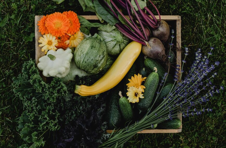 Assortment of fresh organic vegetables and colorful flowers in a box.