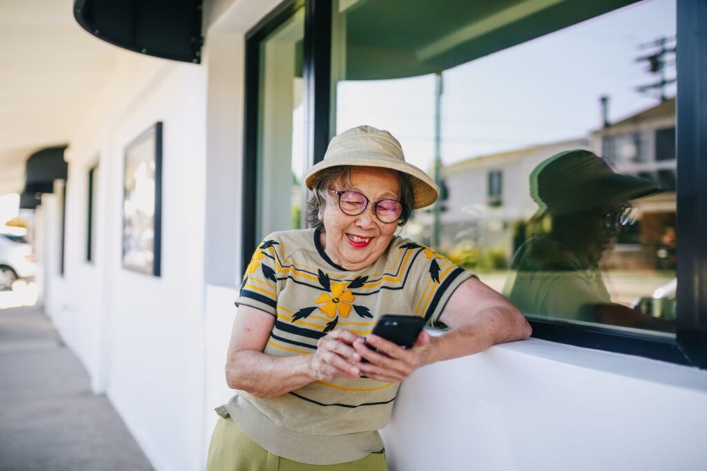 Happy senior woman texting on her phone while enjoying a sunny day outdoors.