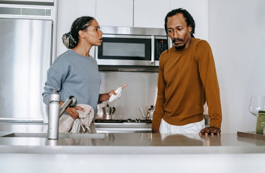 African American guy and lady in casual clothes standing and arguing in kitchen in daytime