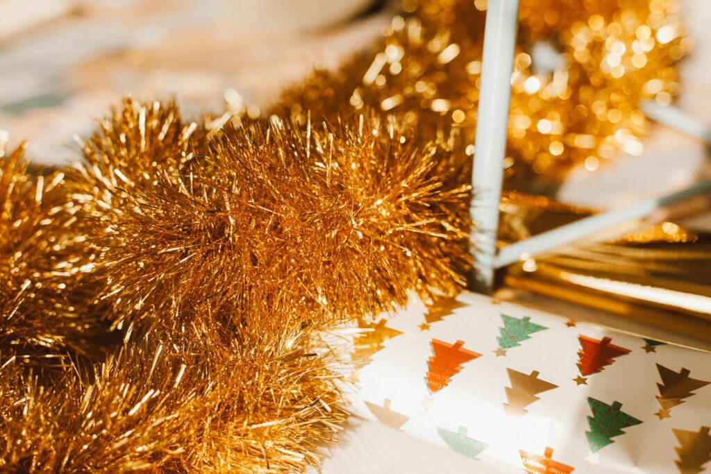Bright gold garland paired with colorful Christmas tree wrapping paper in a close-up festive arrangement.