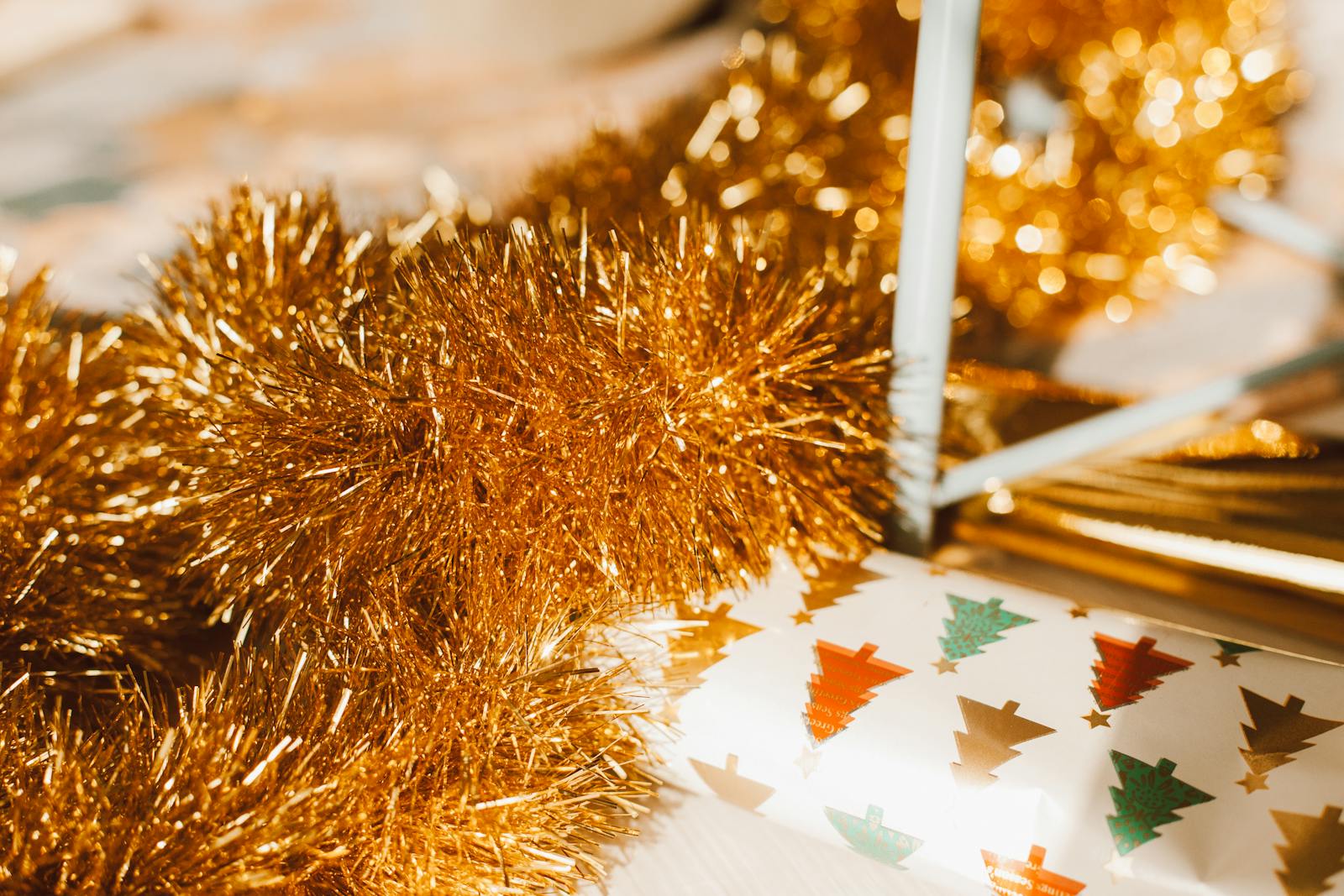 Bright gold garland paired with colorful Christmas tree wrapping paper in a close-up festive arrangement.