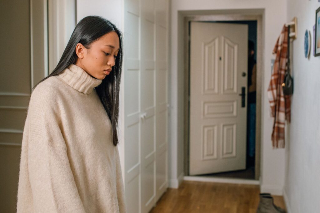 Pensive woman in a turtleneck sweater looking down indoors.