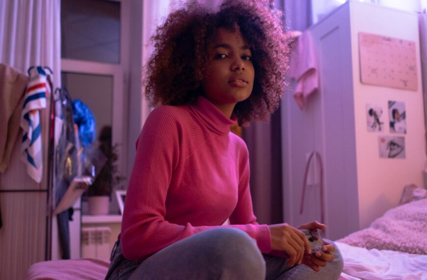 Young woman lounging in a cozy bedroom with a playful pink ambiance.