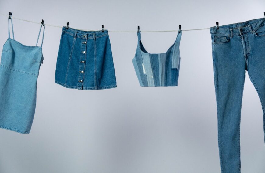 Various denim garments drying on a clothesline against a neutral background.
