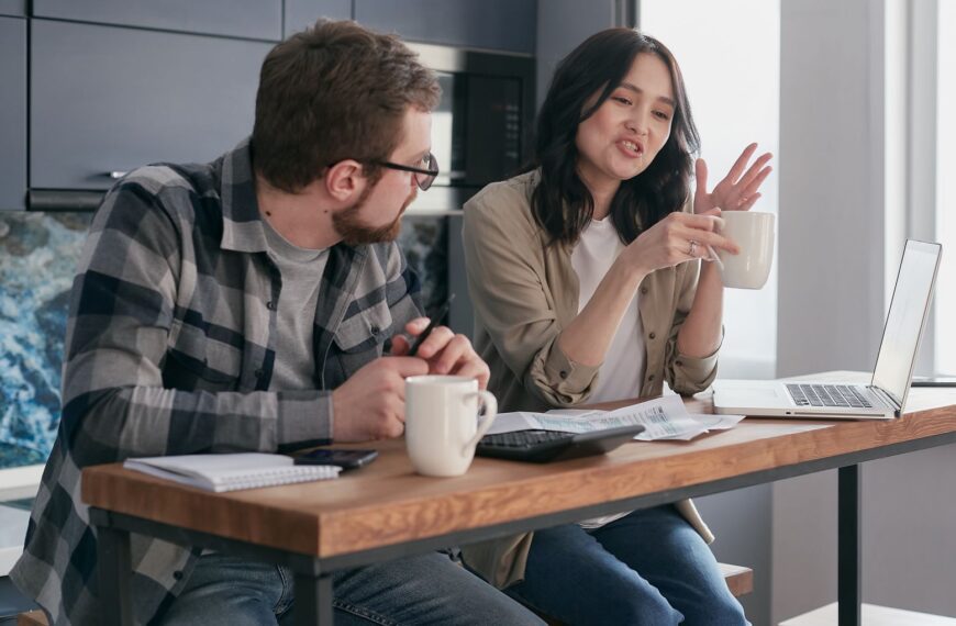 A couple having a discussion with coffee and laptops, reflecting relationship communication indoors.