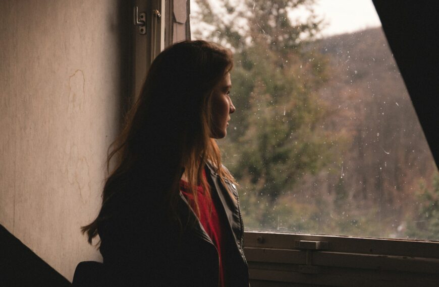 a woman standing in front of a window looking out