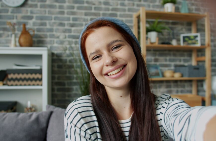 Young woman smiling and taking a selfie indoors