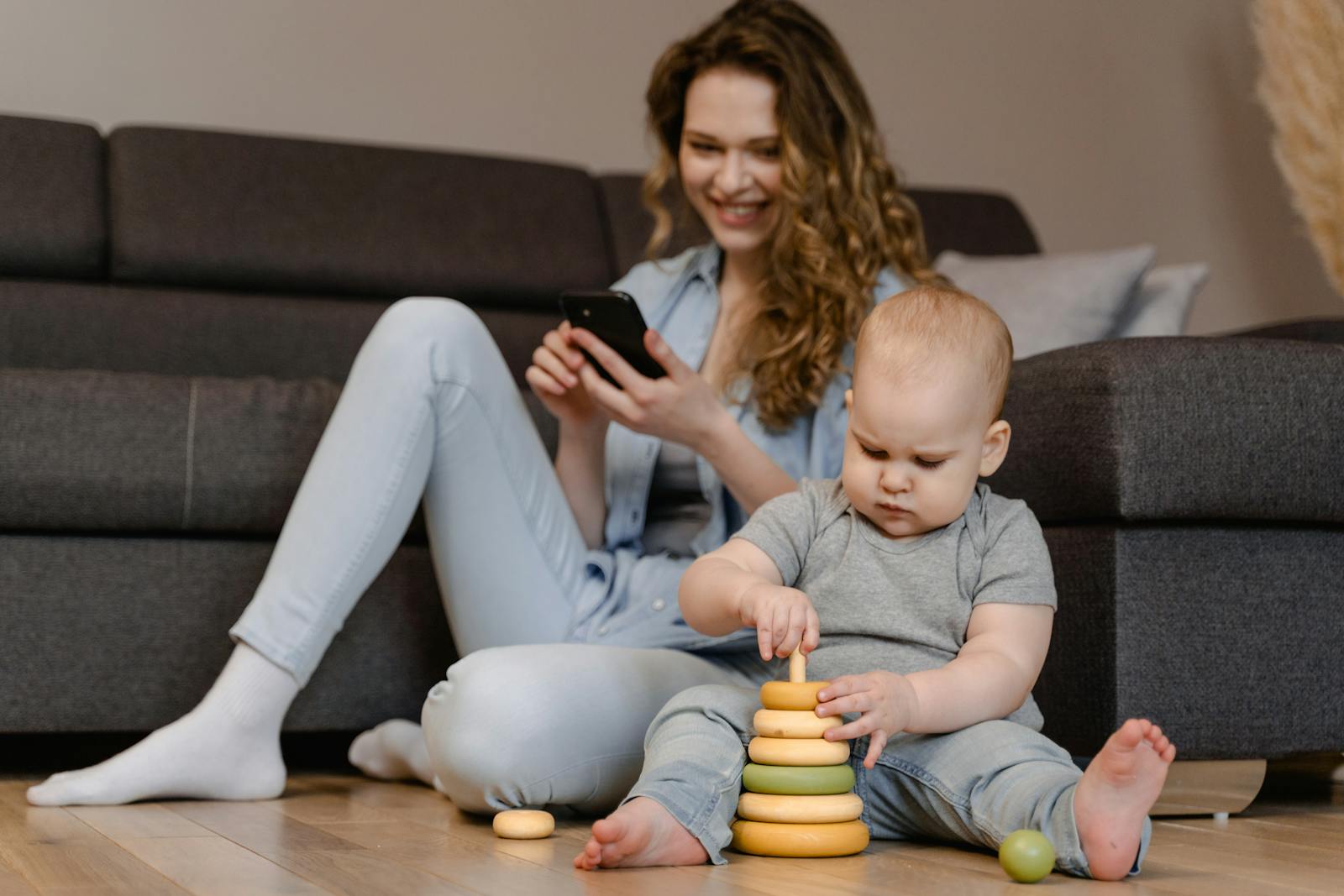 Mother and toddler engaged in playtime with toys on the floor at home.