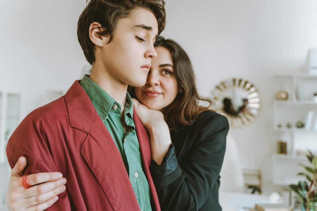 Fashionable young individuals embracing indoors, expressing warmth and style.