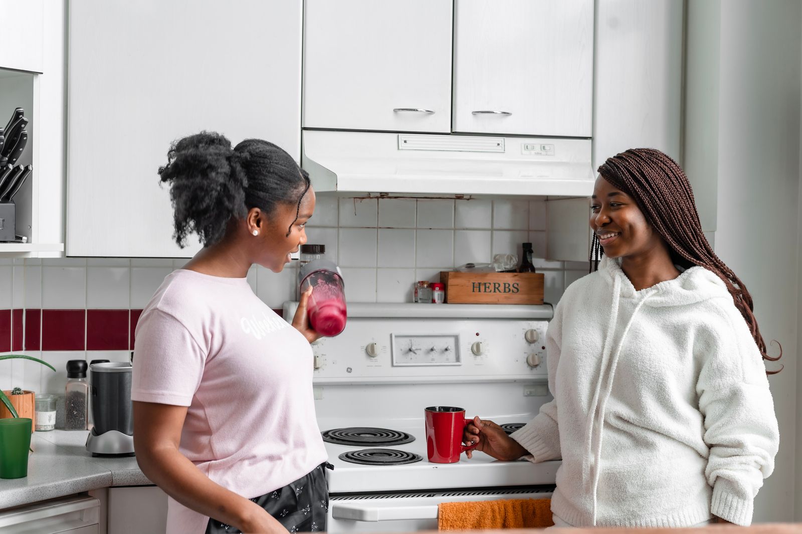 Two women smiling and talking in a modern kitchen, creating a warm and inviting atmosphere.