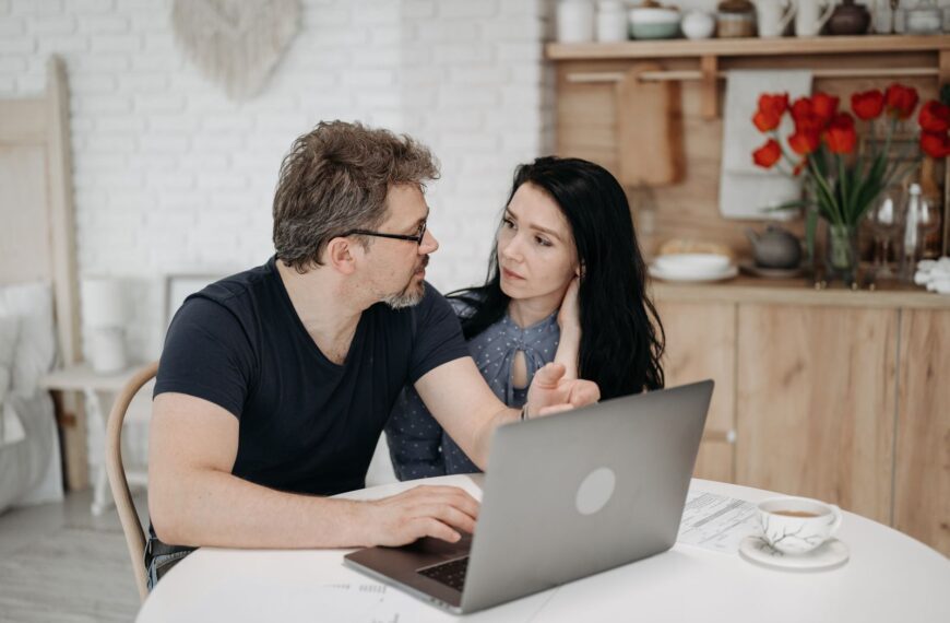 A couple engaged in discussion while using a laptop at a cozy home setting.