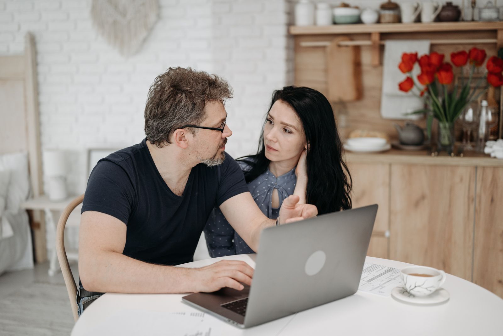 A couple engaged in discussion while using a laptop at a cozy home setting.