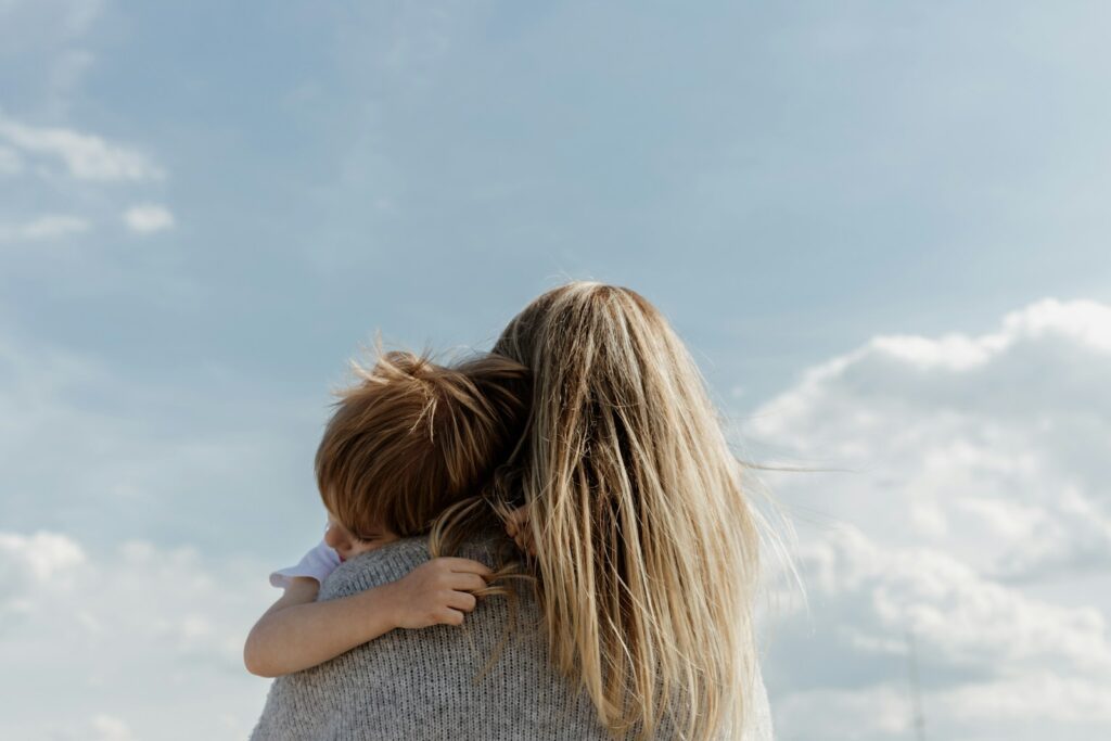 woman holding child from behind against cloudy sky