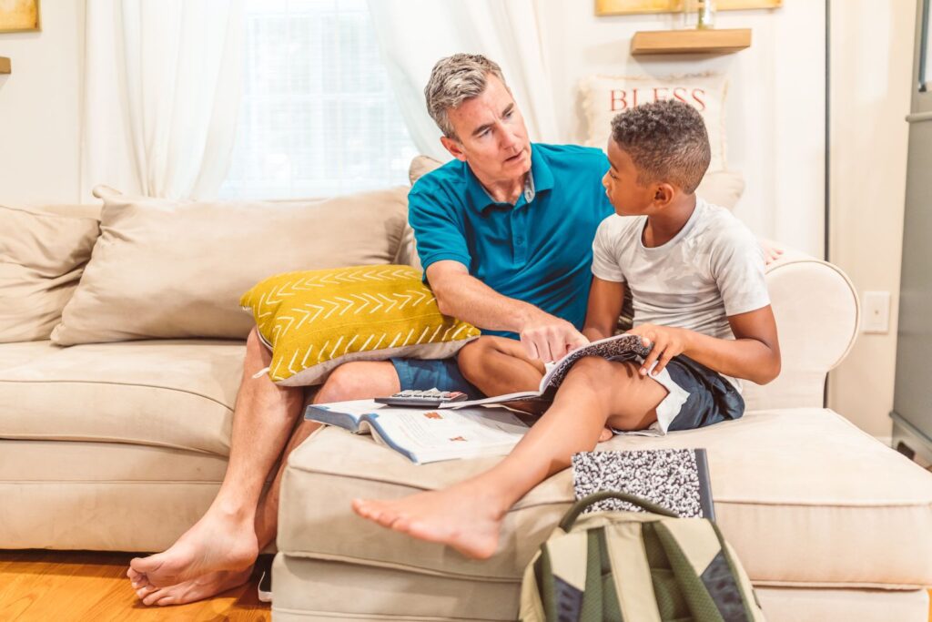 A father and son bonding over books in a cozy living room setting.
