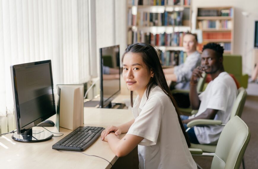 Students engaged in learning at a modern library with computers and natural lighting.