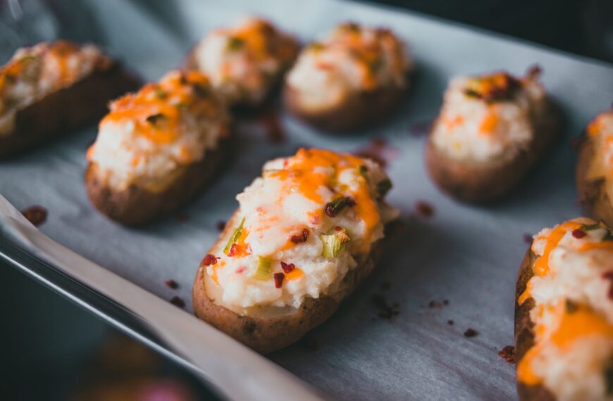 Mouth-watering stuffed baked potatoes with cheese and herbs on parchment paper.