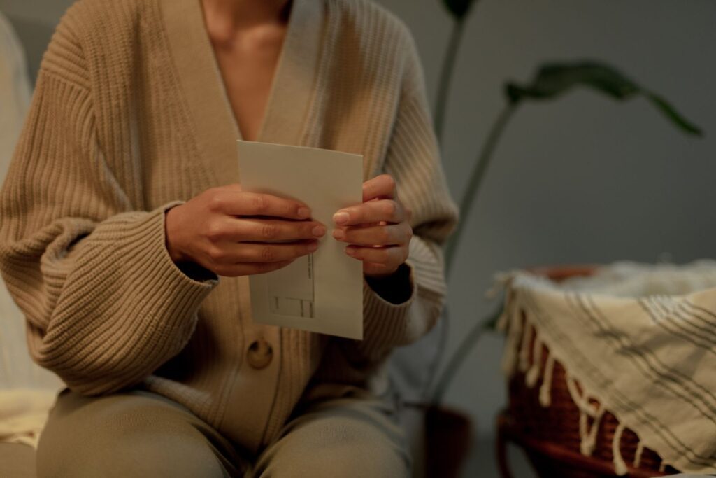 An adult holding a letter indoors, wearing a warm sweater, evoking a cozy mood.