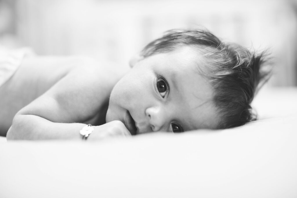 A baby lying on its stomach looking at the camera