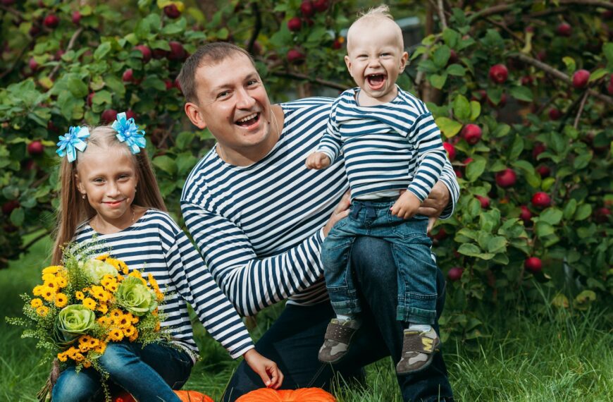 a person and two children sitting on a bench in front of a tree