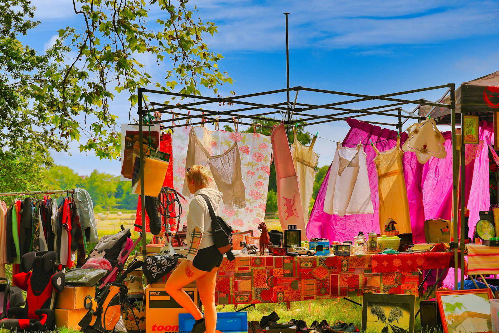 Woman browsing clothes at an outdoor market stall.
