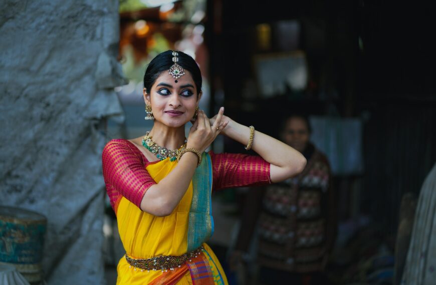 A woman in a yellow and red sari talking on a cell phone