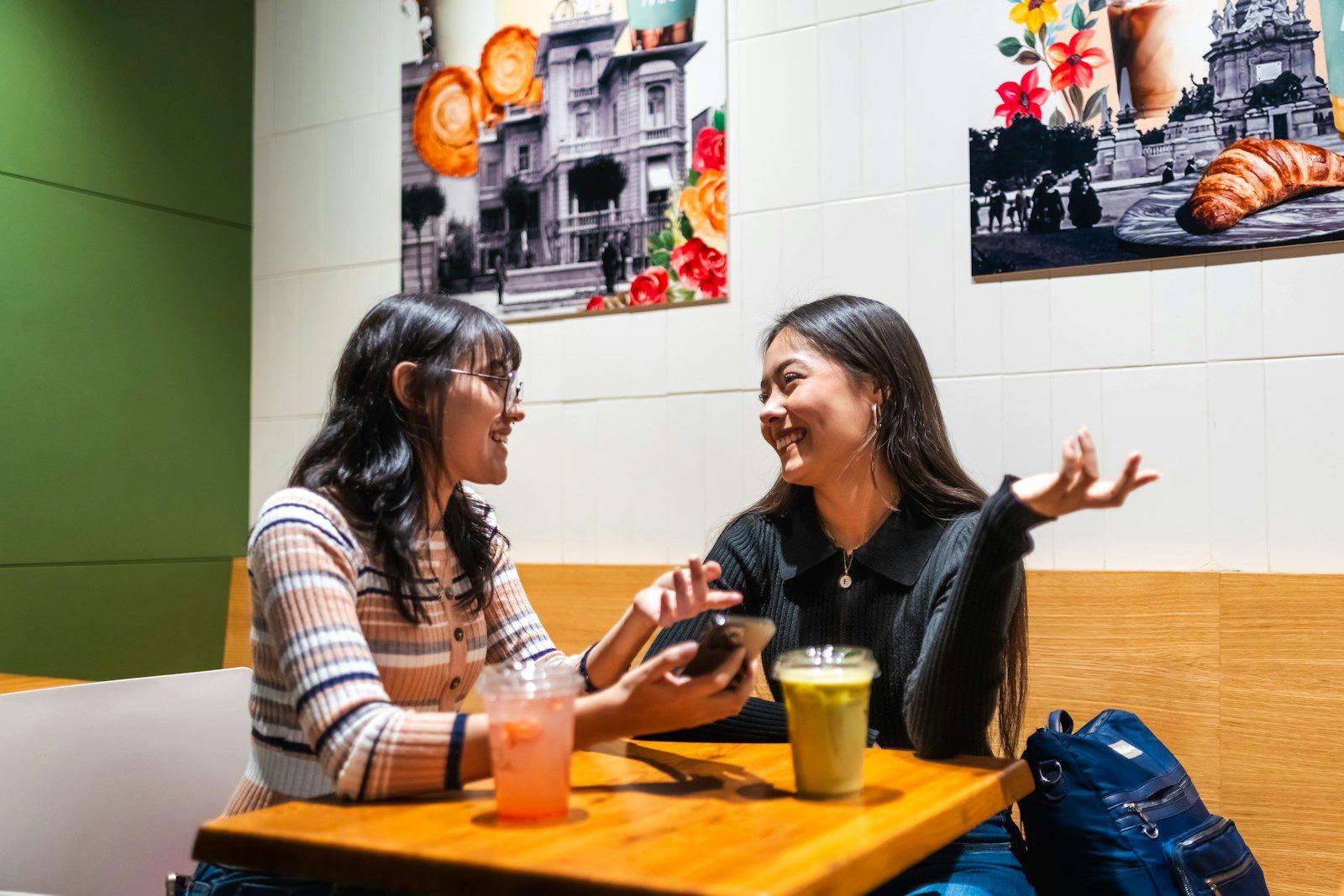 Two young women talking at a cafe table.