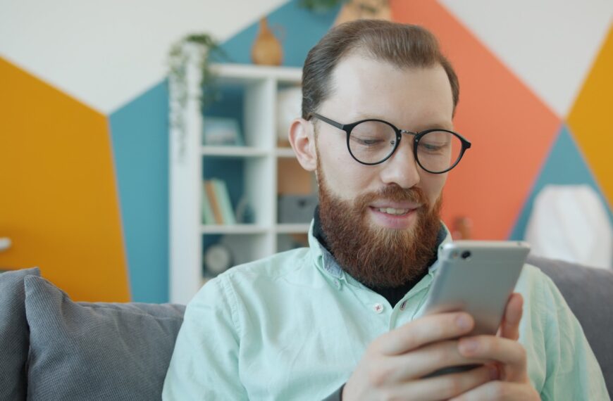 Man with beard and glasses using smartphone on smartphone.
