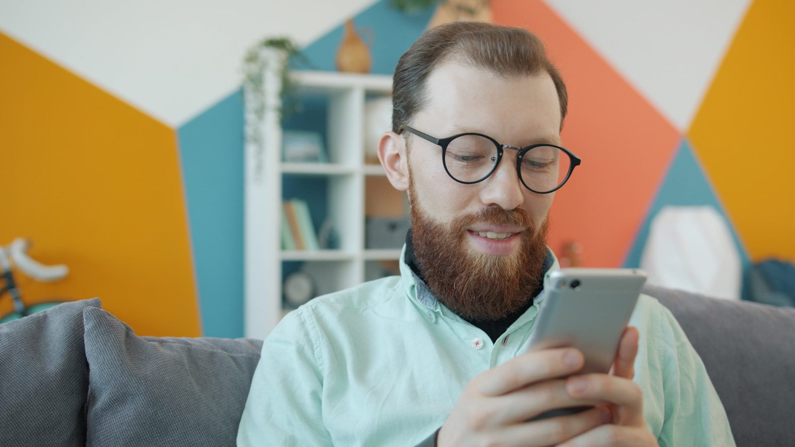 Man with beard and glasses using smartphone on smartphone.