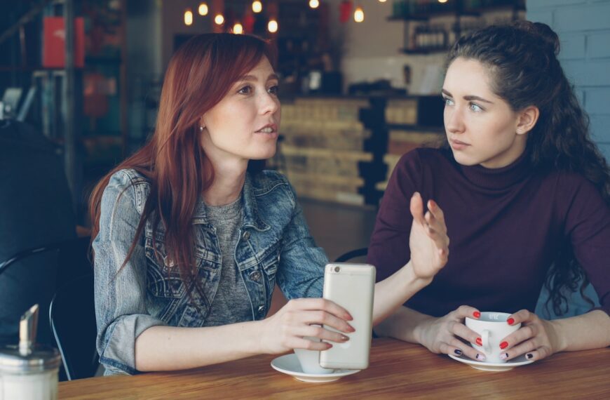 Two women converse at a cafe.