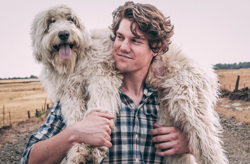 man carrying long-coated white dog