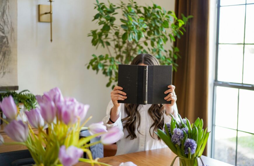 a woman sitting at a table reading a book