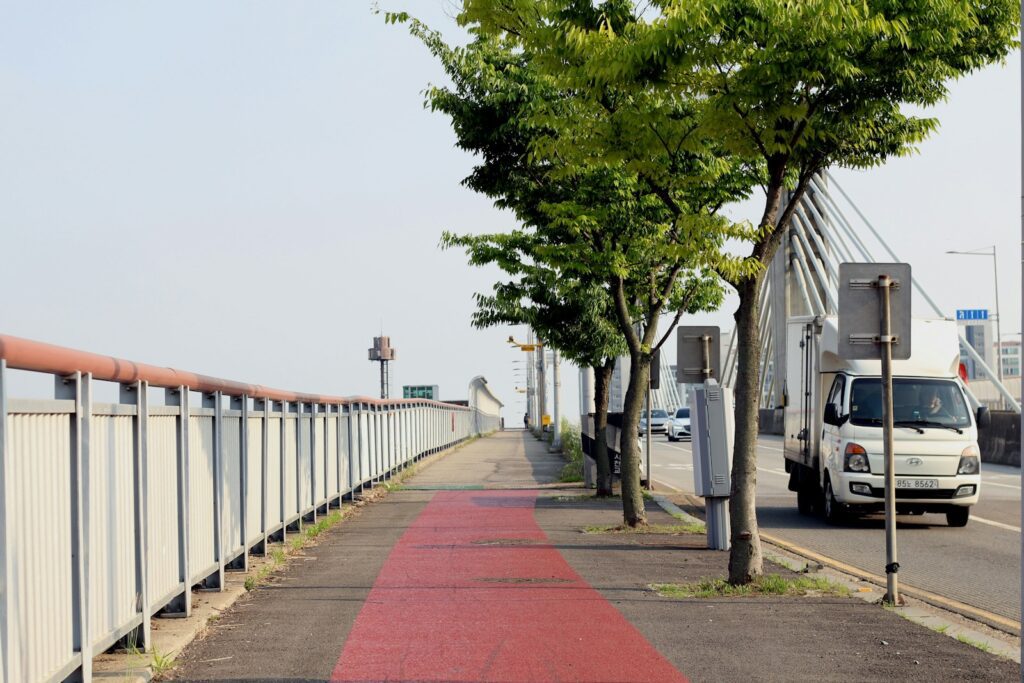 Red path, fence, trees, and a road with a truck.