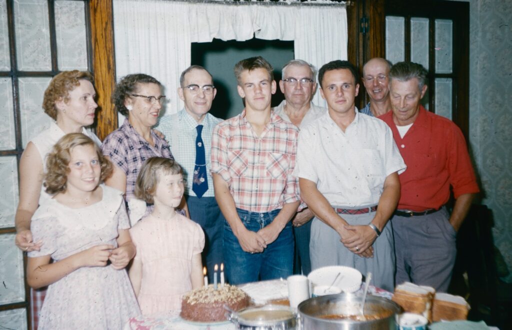 a group of people standing in front of a cake
