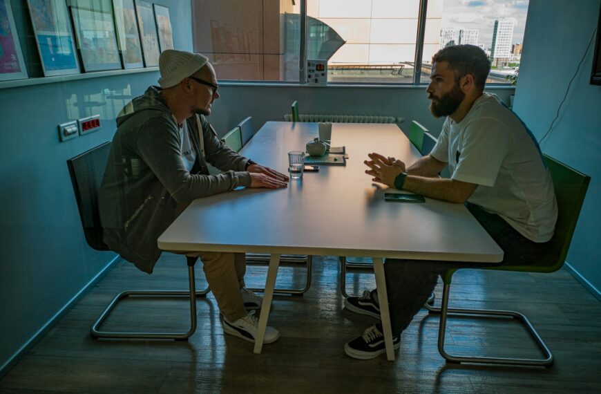 man in black jacket sitting beside man in gray jacket