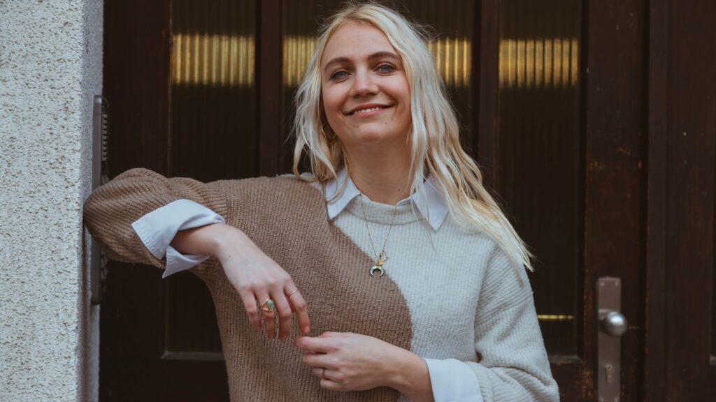 a woman standing in front of a door wearing a sweater