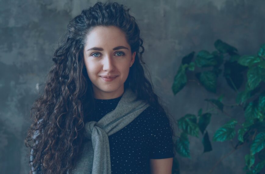 A woman with curly hair smiles at the camera.