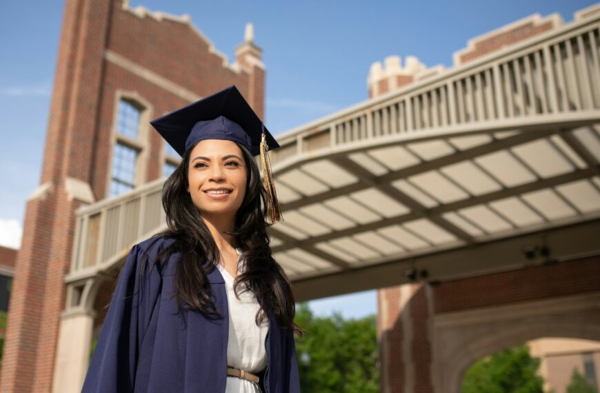 a woman in a cap and gown standing in front of a bridge