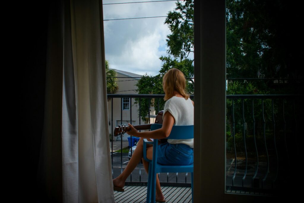 A woman plays a string instrument on a balcony.