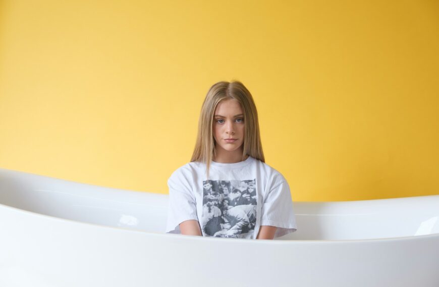 woman in white and black floral shirt sitting on bathtub