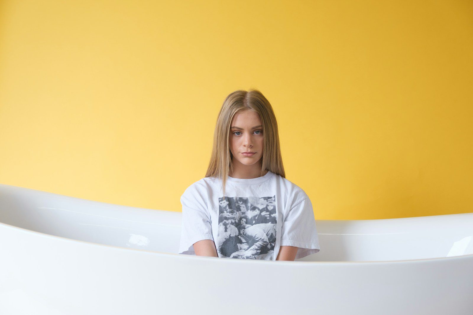 woman in white and black floral shirt sitting on bathtub