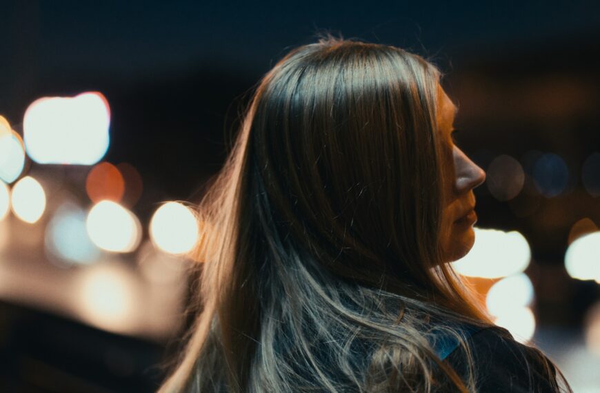 A woman standing in front of a street at night
