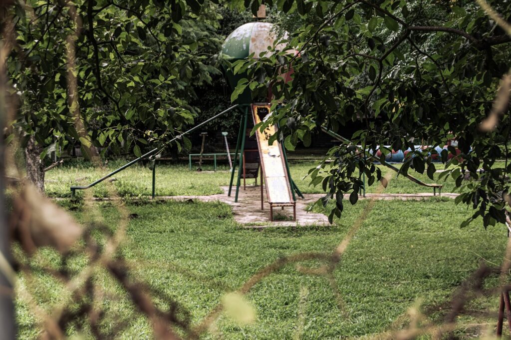 An old playground slide sits in a grassy yard.
