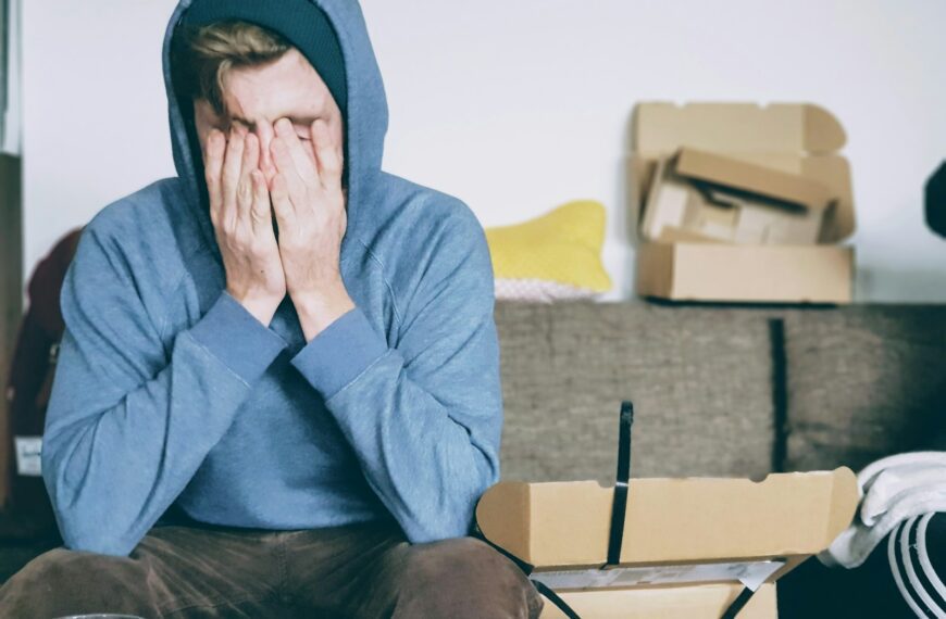 man covering face with both hands while sitting on bench