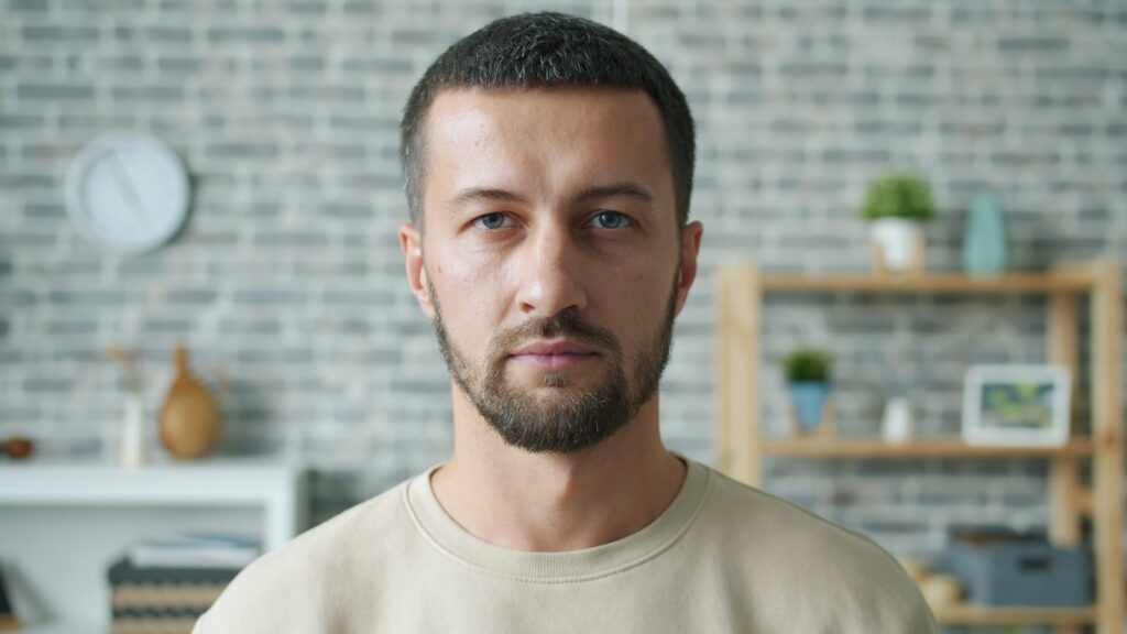 A man with a beard looks directly forward.