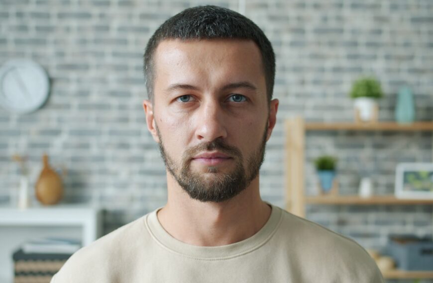 A man with a beard looks directly forward.