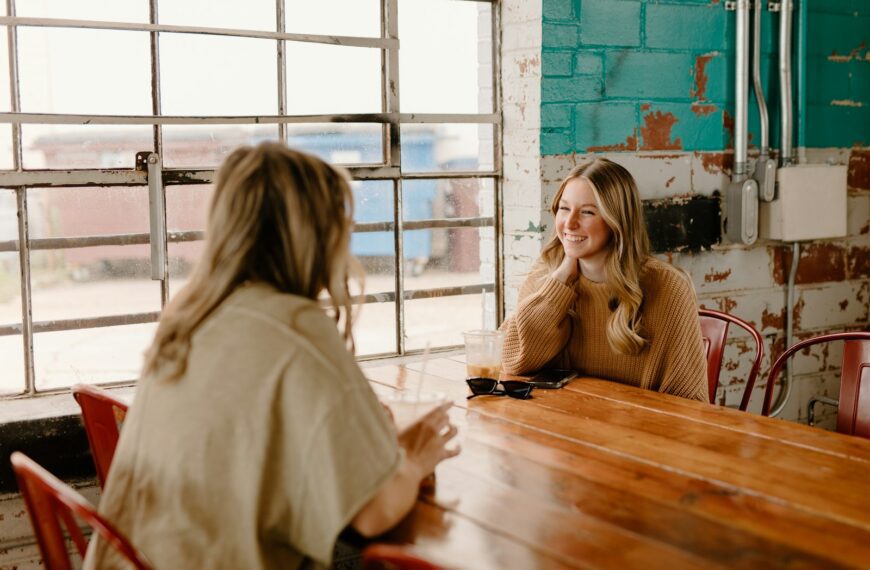 a woman sitting at a table talking to another woman