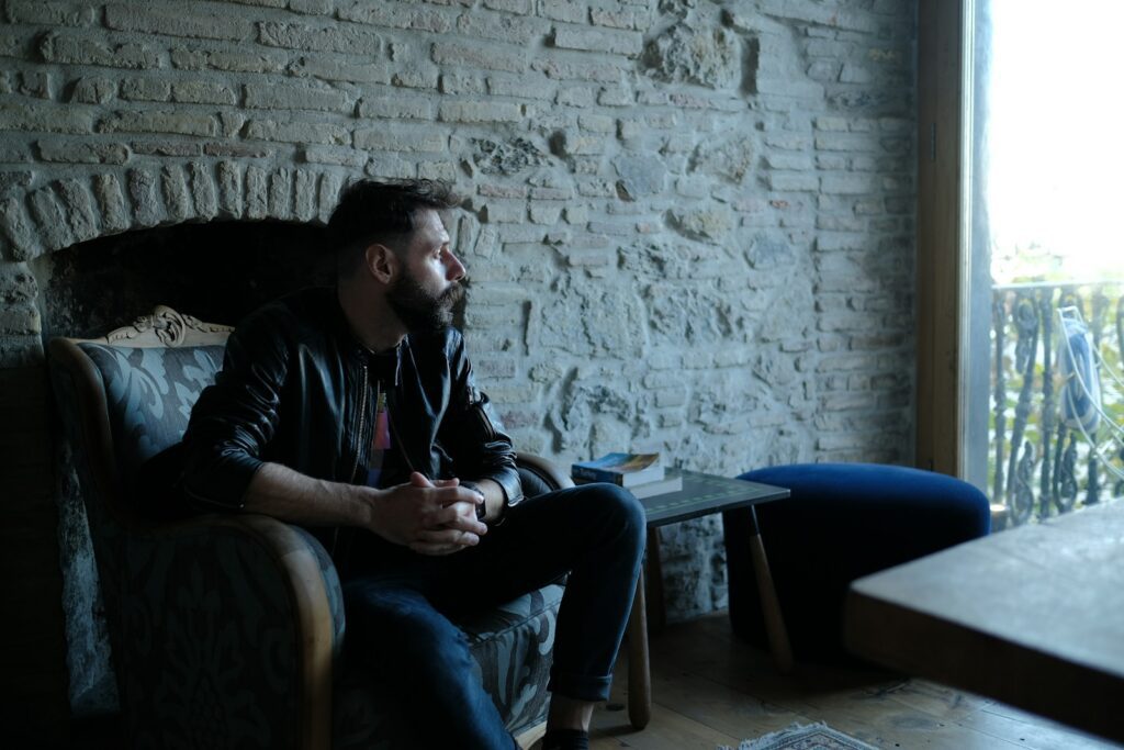 man in black jacket sitting on blue couch