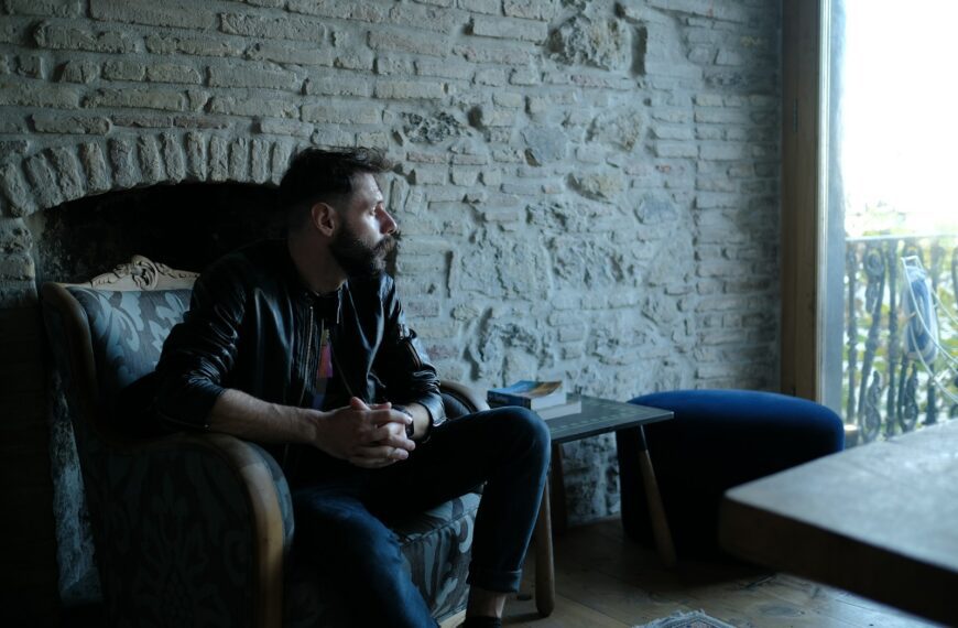 man in black jacket sitting on blue couch
