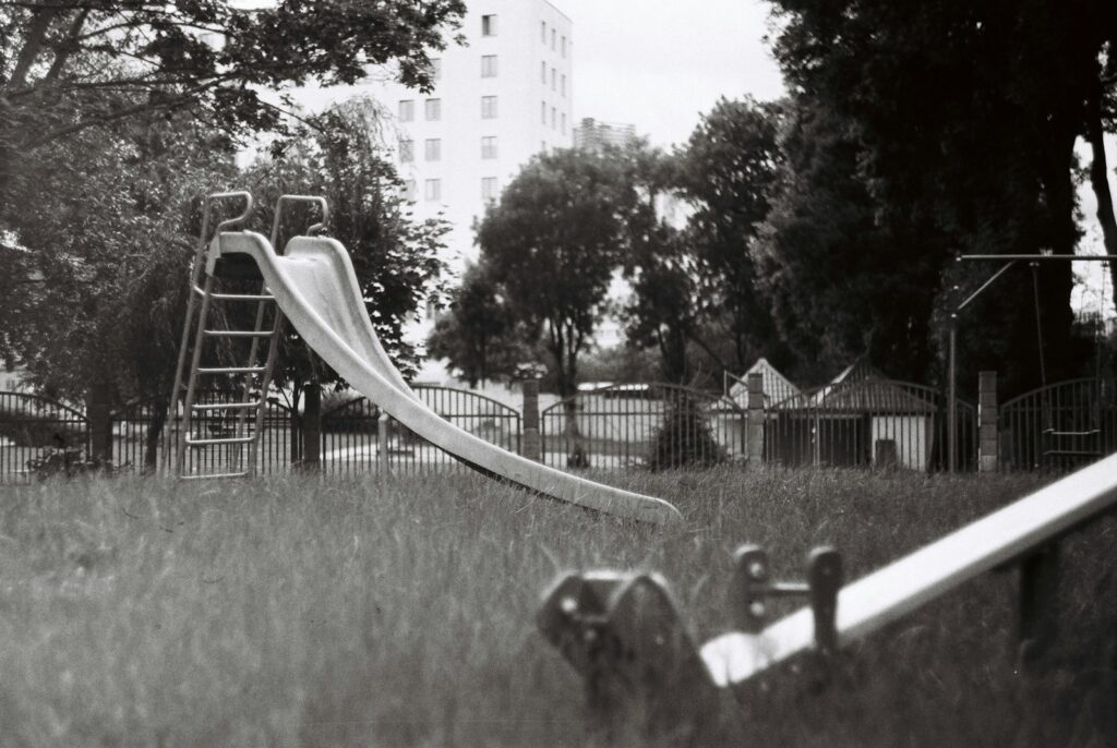 A black and white photo of a playground with a slide